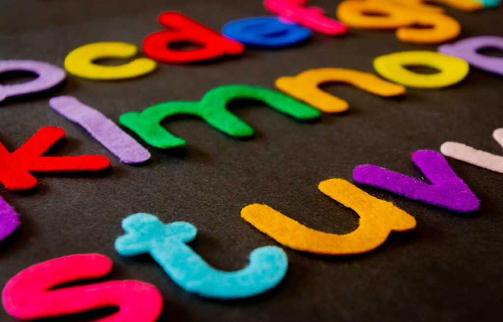 Bright and colorful felt alphabet letters arranged on a dark surface, perfect for educational and creative projects.