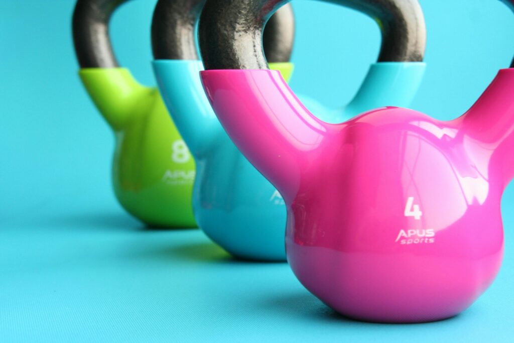 Vibrant colored kettlebells on blue background highlighting fitness and exercise equipment.