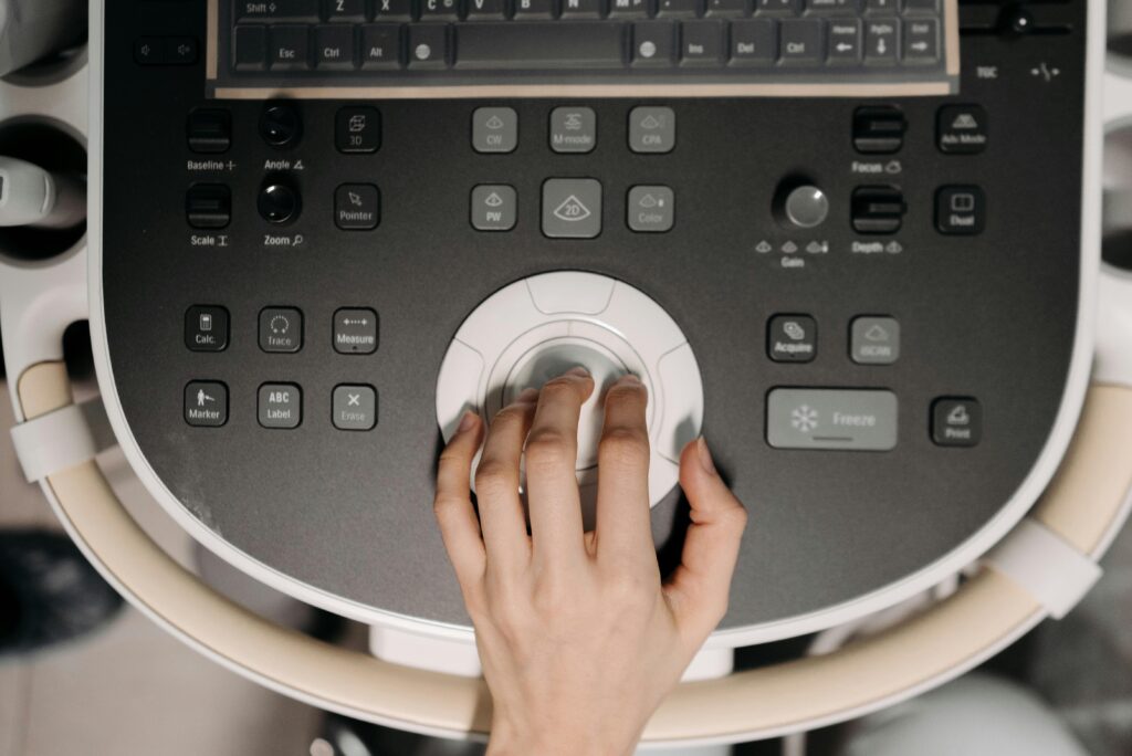 Close-up of hand operating ultrasound machine, illustrating medical technology usage.