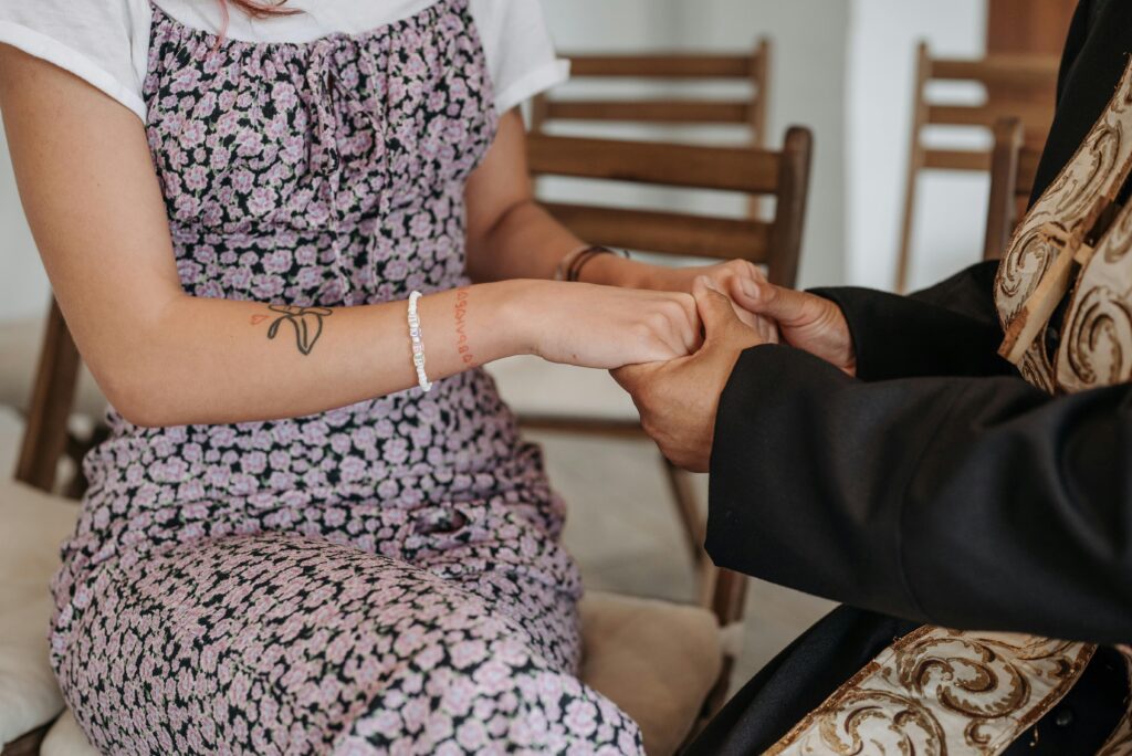 A priest and parishioner share a moment of spiritual connection through holding hands.